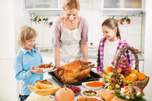 A mom and her children standing next to their thanksgiving feast