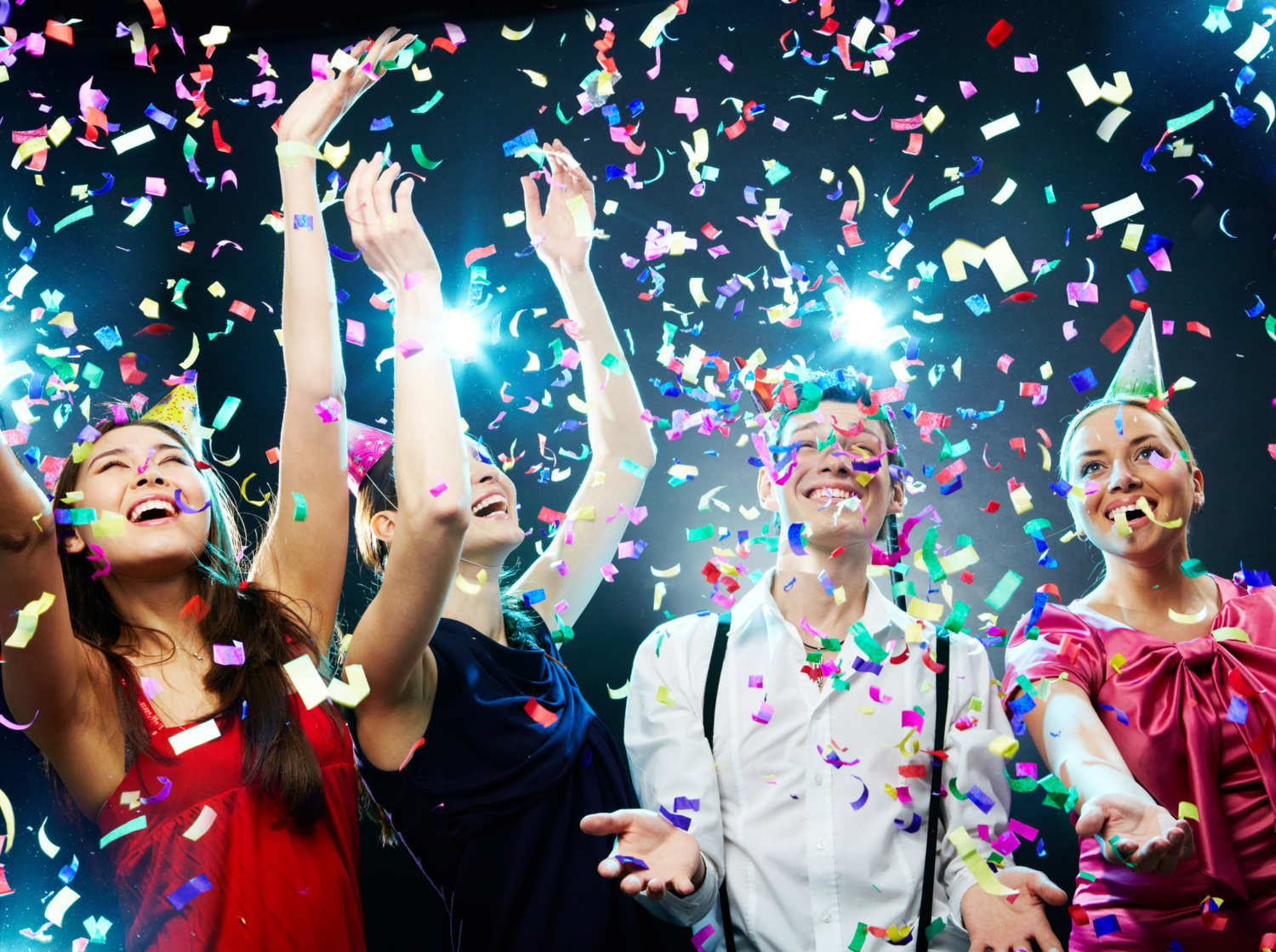 A group of individuals at a birthday party, in party hats, with confetti going everywhere