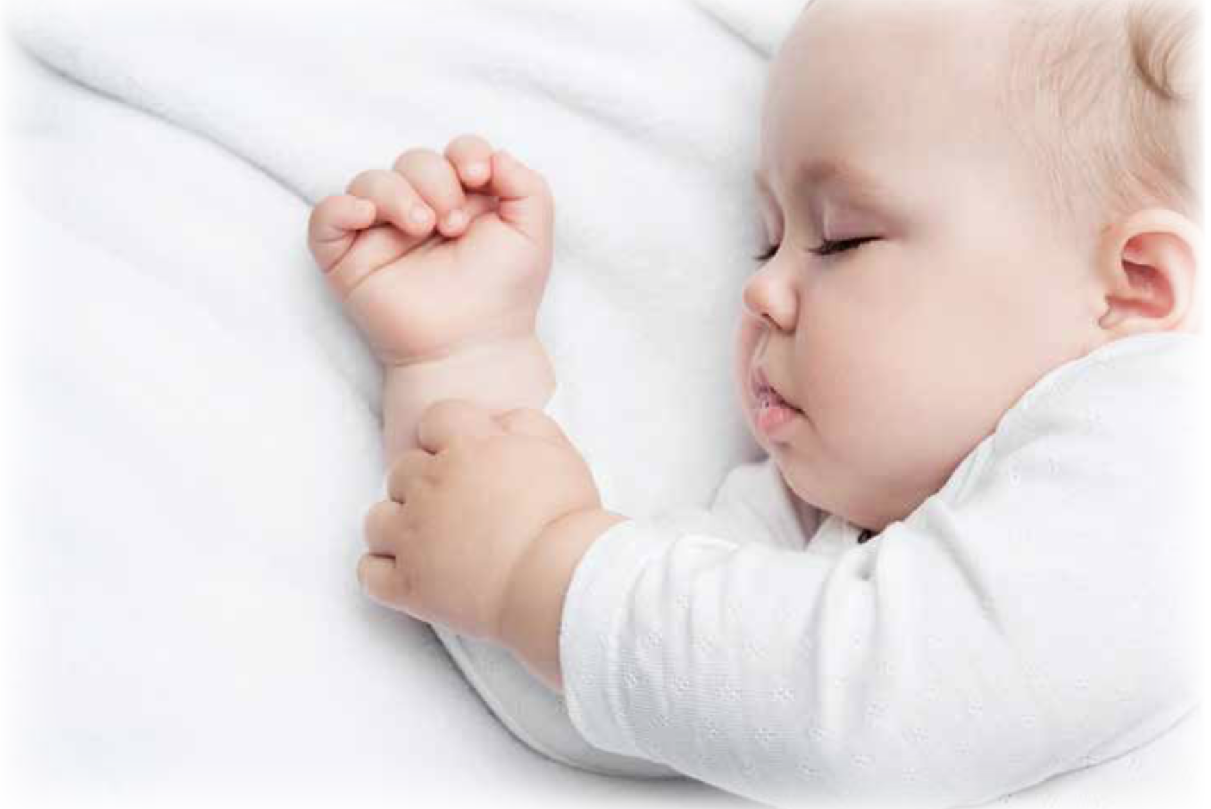 A sleeping infant, with his tongue sticking out and his hands laying together