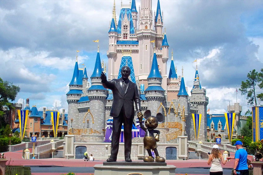 A picture of Walt Disney & Mickey in front of the disney world castle