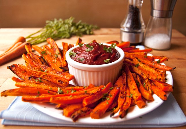 A nice plate of carrot fries with some dipping sauce in the middle