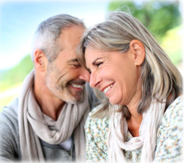 An older couple sitting next to each other smiling at each other