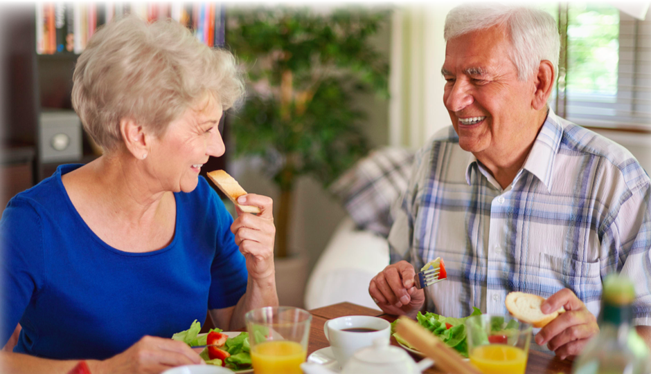 An older lady and her husband eating some salad and bread together