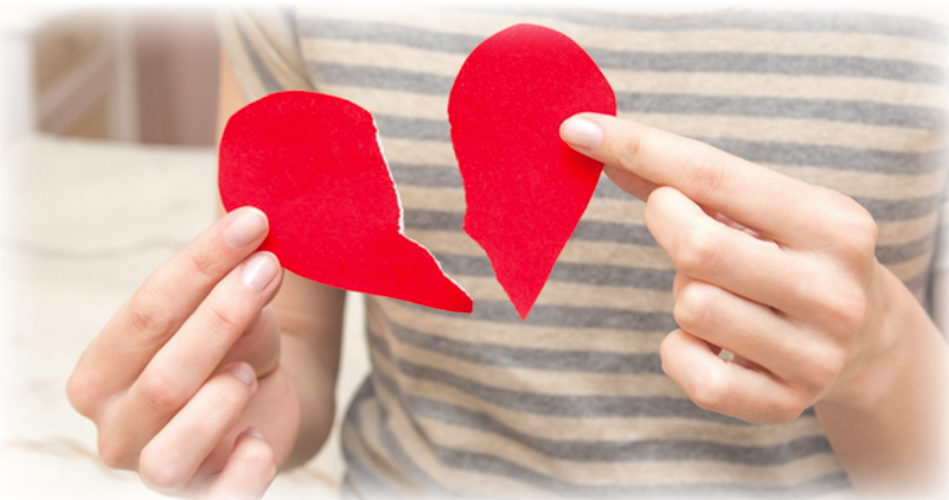 Someone holding a paper heart, with a tear down the middle
