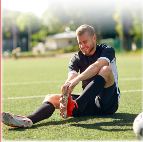 A man on a turf field holding his foot in pain