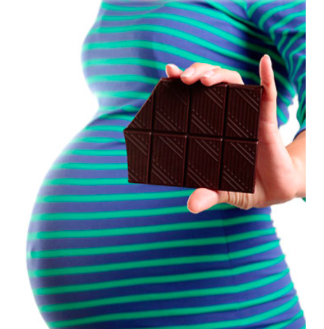 A pregnant lady holding a sliver of dark chocolate