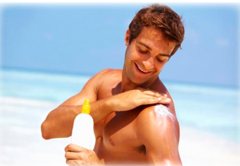 A man applying sun block to his shoulder at the beach