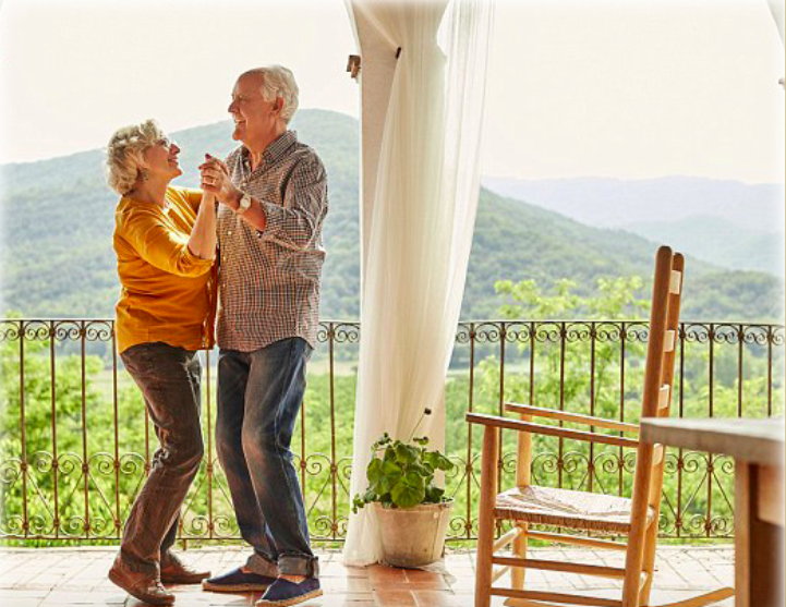 An older lady and man dancing together on a balcony