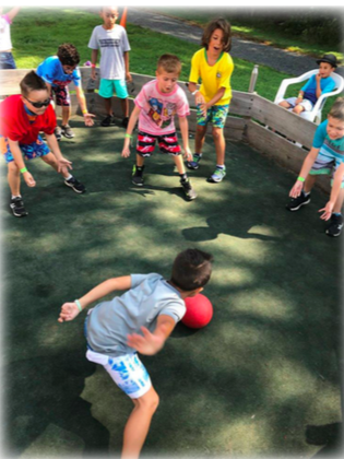 A group of boys surrounding a kickball playing