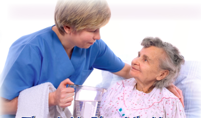 A nurse looking down at an older lady who is in hospital clothing