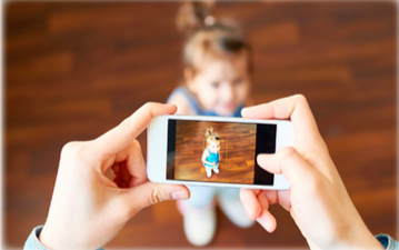 A parent taking a photo of her child with her phone