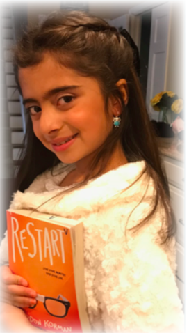 a student standing and smiling with a book titled "restart"