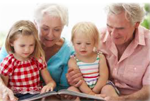grandparents sitting with their grandchildren reading a book