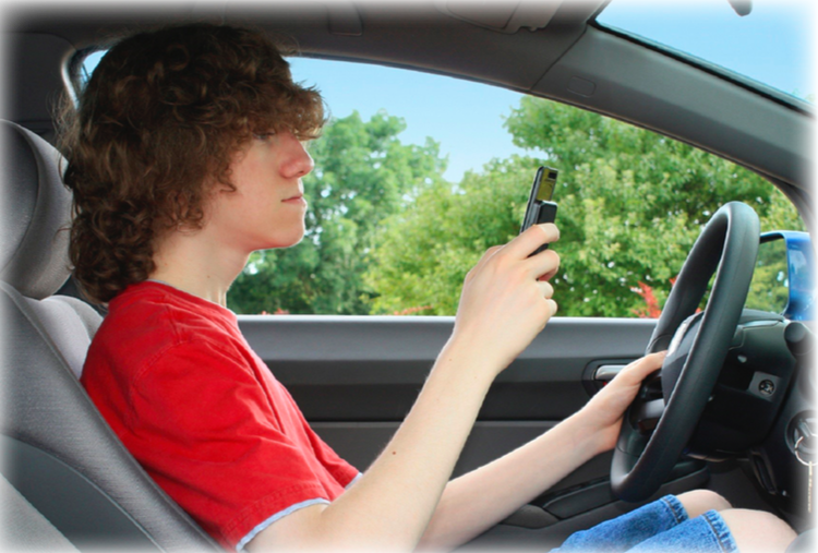 A boy with a red shirt in a car, driving while he's on his phone