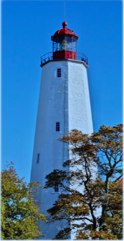 A lighthouse on a clear day, with a few trees in front