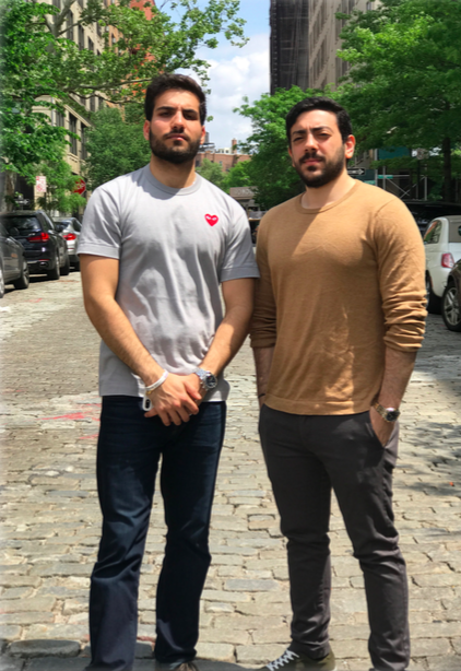 two men standing next to each other on a cobblestone road