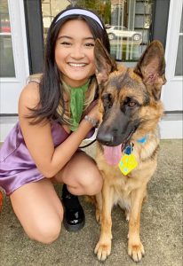 A picture of a girl dressed up as daphne from scooby doo and her dog in a scooby doo collar
