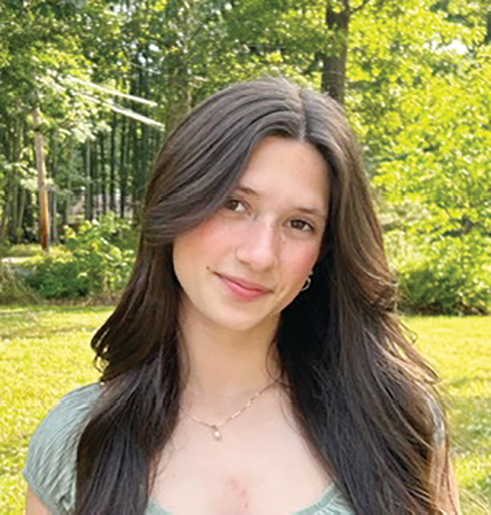 A girl standing with her head tilted in the forest
