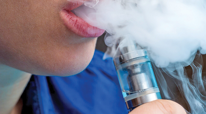A photo of vapor being exhaled from someone's mouth from an E-cigarette