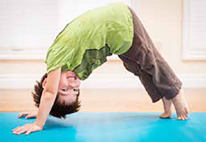 A child amidst a yoga class in the downward dog stance.
