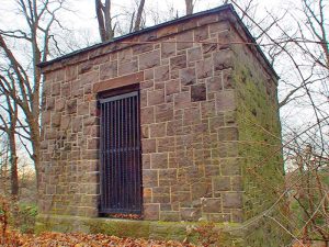 A small brick building with a locked gate protecting it