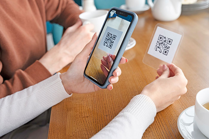 someone holding a phone in attempt to scan a qr code that they are holding in the other hand