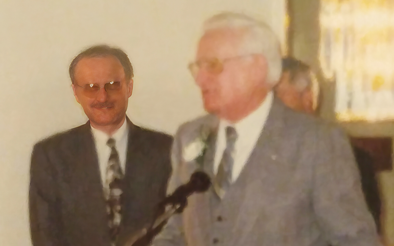 A Picture of a man standing next to his father at a podium, zoomed in closer