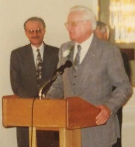 A Picture of a man standing next to his father at a podium