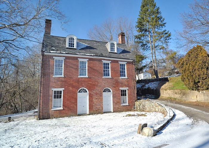 A brick house with two chimneys in the snow
