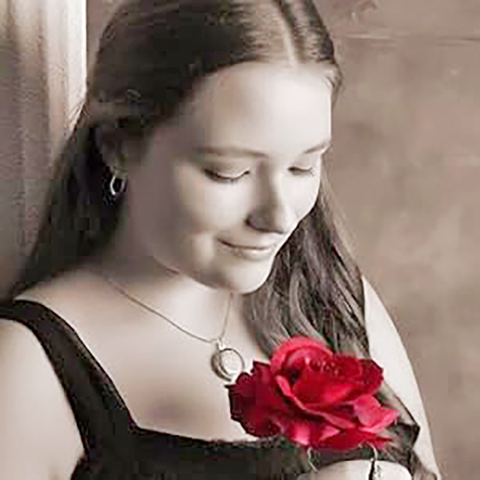 A girl holding a red rose, staring at it intently.